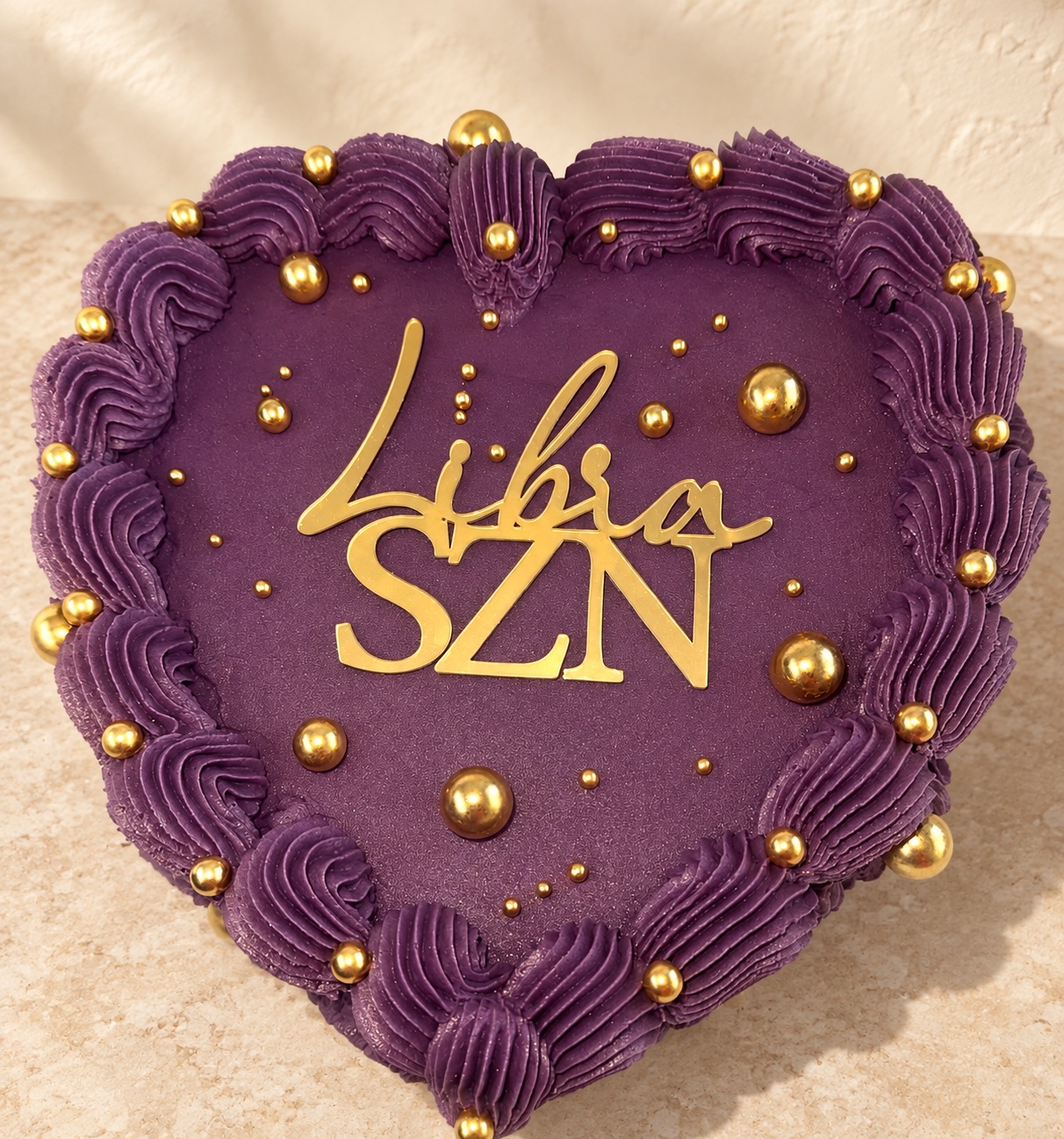 Purple heart-shaped celebration cake with gold decoration