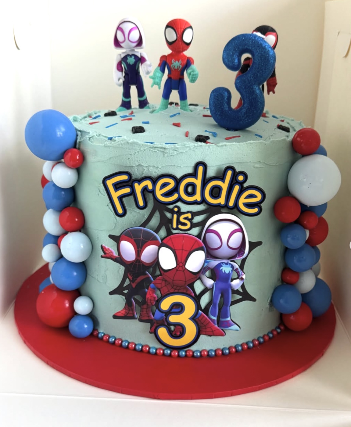Blue superhero-themed third birthday cake